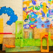 Brightly-colored textured floor objects and wall art displayed as part of an exhibit in Patterson Gallery located on Penn State University Park campus.