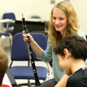 School of Music student teacher helping elementary students during rehearsal.