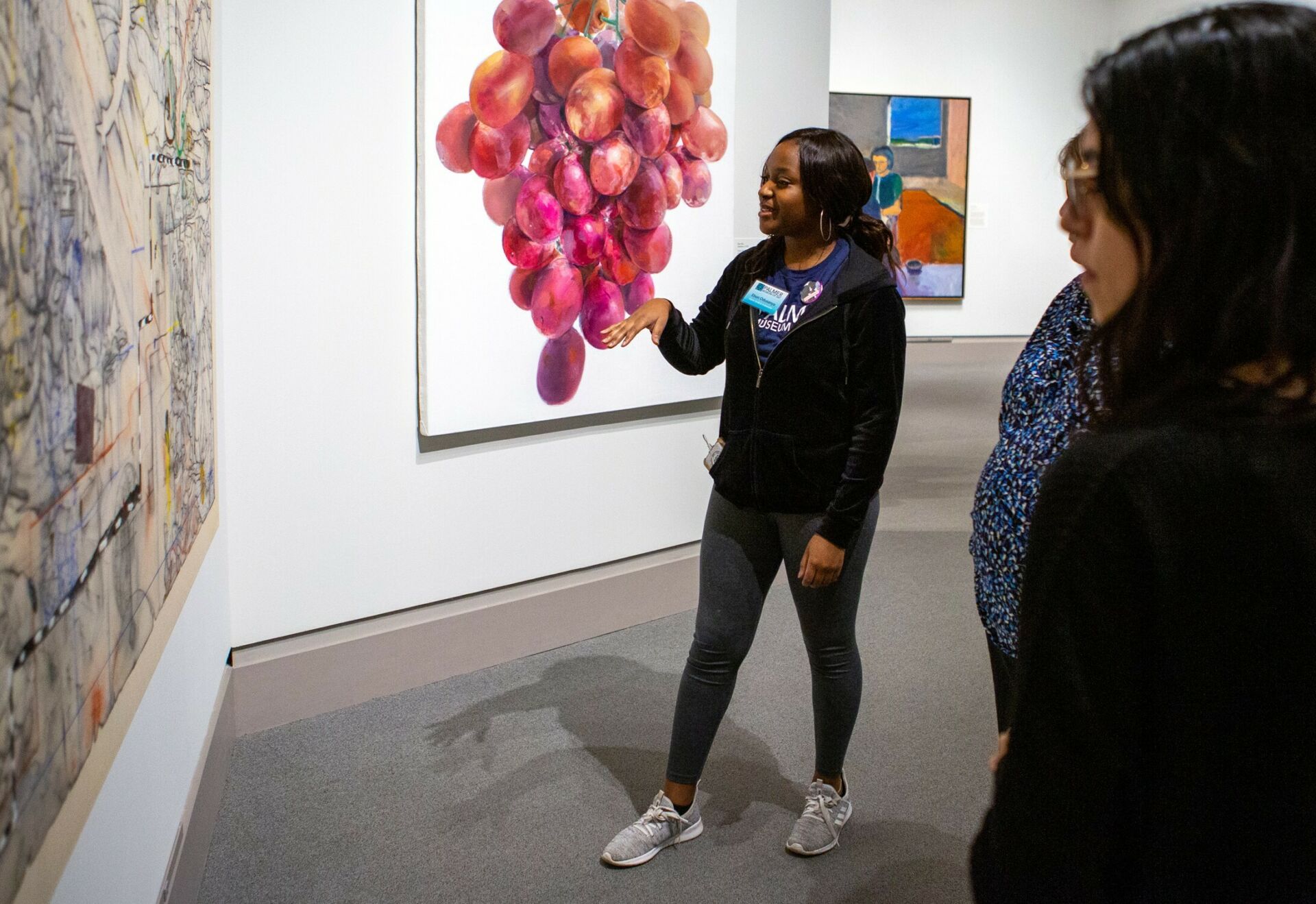 A public collection of late artwork displayed at the Palmer Museum of Art. A student explains the meaning of the piece to visitors.