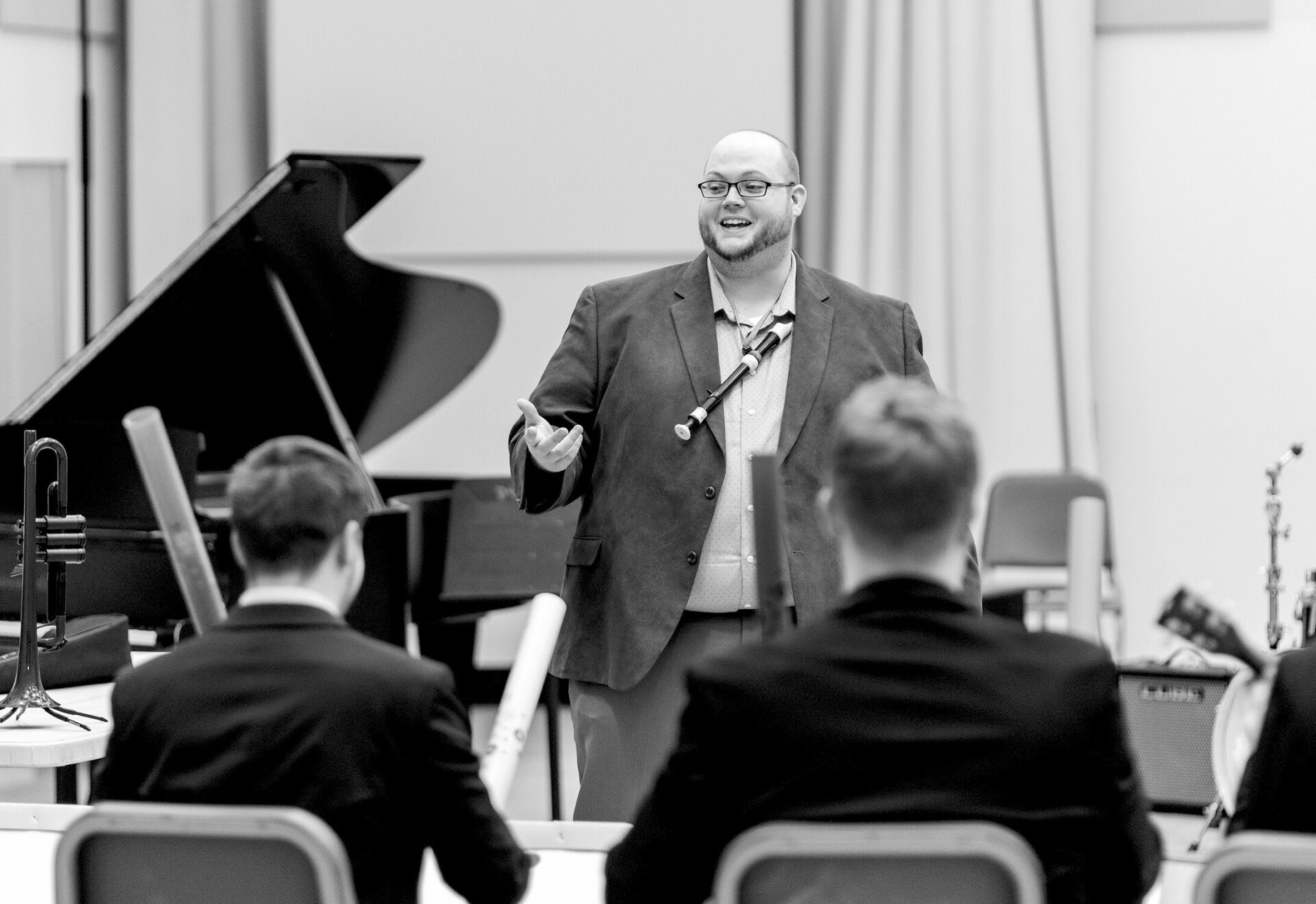 A music education Ph.D. student teaching in front of a group of musicians with instruments.