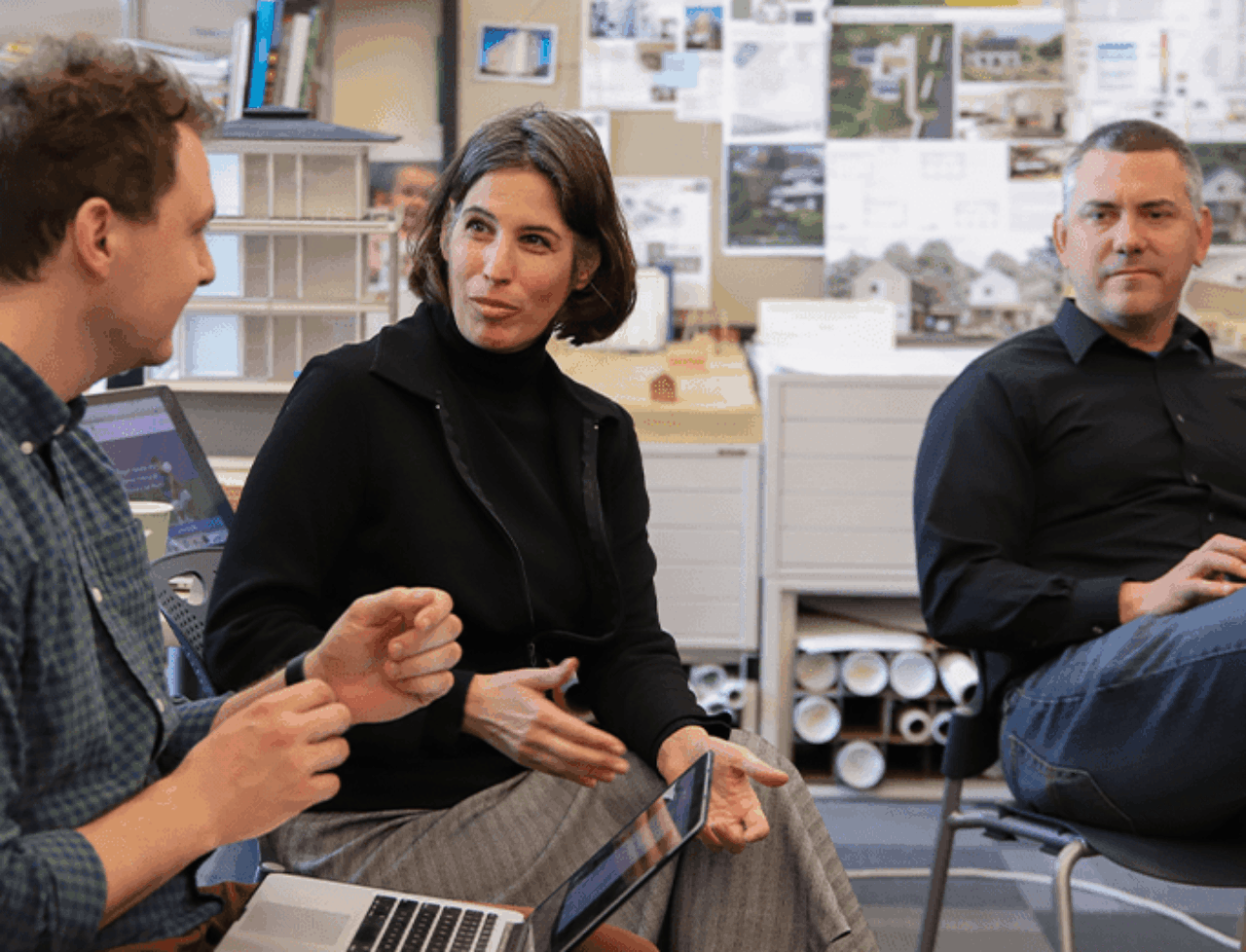 Lisa Iulo is pictured speaking to someone on her right who has a laptop on his lap while a community member looks on.