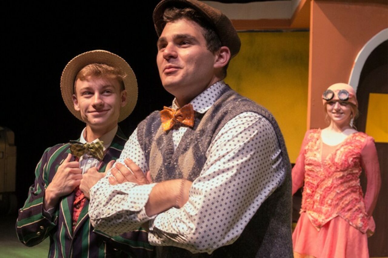 Three actors, two i nthe foregraound and one looking on from the background, in a performance of Frog and Toad.