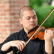 A photograph of Jonathan Livioco outside playing his viola.