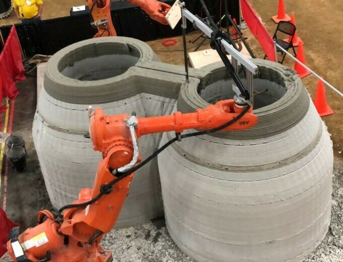 Orange multi-axis industrial CNC robots being used for 3d-printing concrete forms.