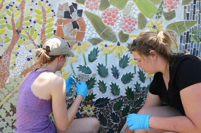 Students work outside on Dani Spewak's Morning Star House Public Art Installation, which showcases bright green leaves and flowers.