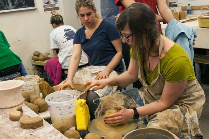 Students literally up to their elbows in clay while wheel throwing pottery in the School of Visual Arts ceramics studio.