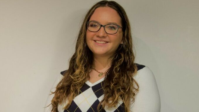 Head shot of a young white woman with long brown hair and glasses.