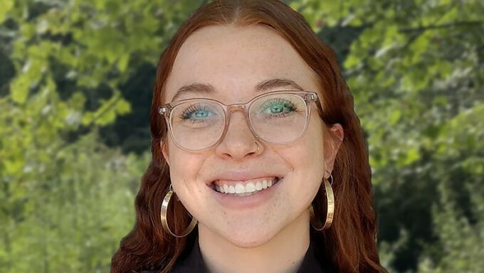 Girl with red hair and glasses smiling