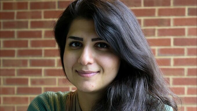 Portrait of Mina Rahimian in front of a red brick wall.