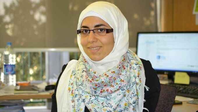 A photo of Dima Abu-Aridah in a headscarf, sitting in front of a computer.