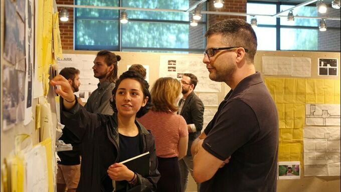 A female landscape architecture student points to her design during a critique with a male landscape architecture faculty member.