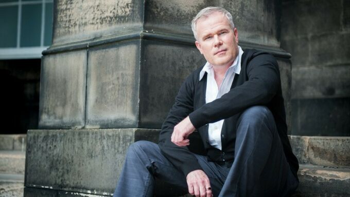 A photograph of Paul Daniel Marriott sitting on the steps of a building.