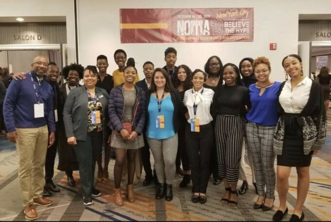 Group of people standing in front of a NOMA '19 banner with Meghan Davis in the front, center.