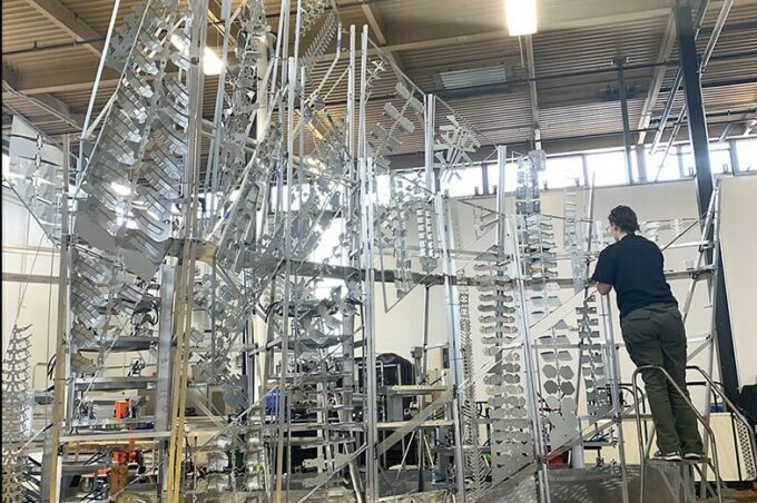 Becca Newburg on a ladder, assembling the walls to the framework of the chapel, in which the steel drums reside, in the Laundry Building.