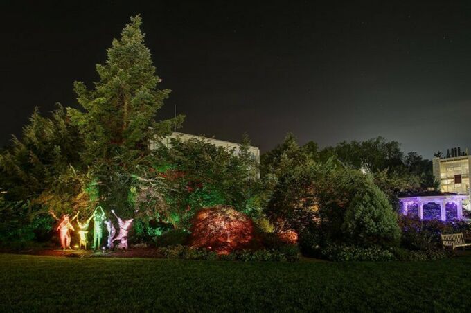 The children statues in Hintz Alumni Garden lit by multiple colors as designed by Stella Murray for her Nittany Lights project.