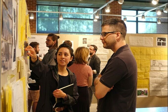 A female landscape architecture student points to her design during a critique with a male landscape architecture faculty member.