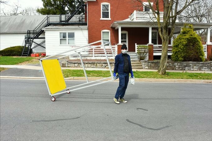 Marcus Shaffer wheels the completed frame through the streets of downtown State College to drop it off for Jamie Heilman in a mask and gloves.