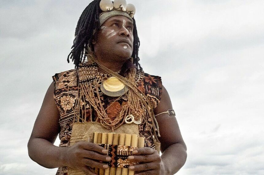 A man wearing a coastal headdress looks off into the distance.