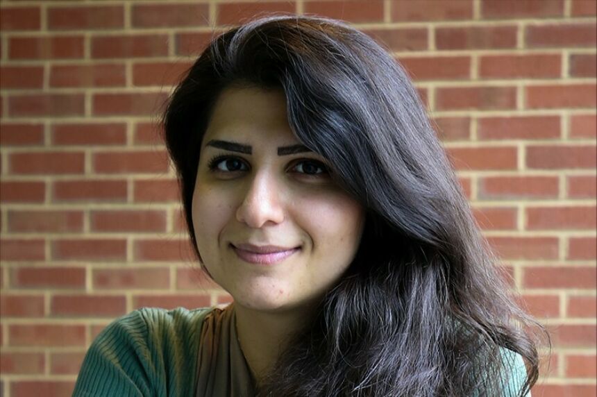 Portrait of Mina Rahimian in front of a red brick wall.