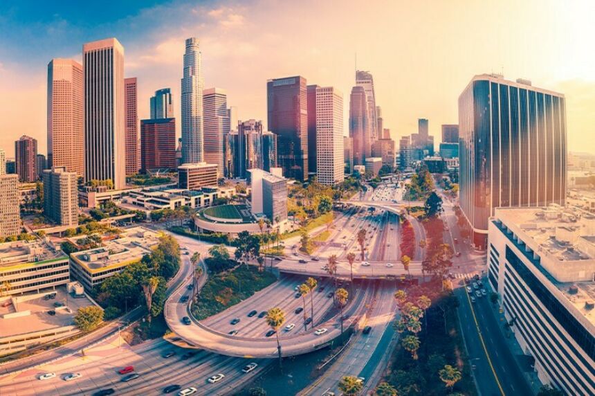 The skyline of Los Angeles lit from behind by the sun with the bypass system in the foreground.