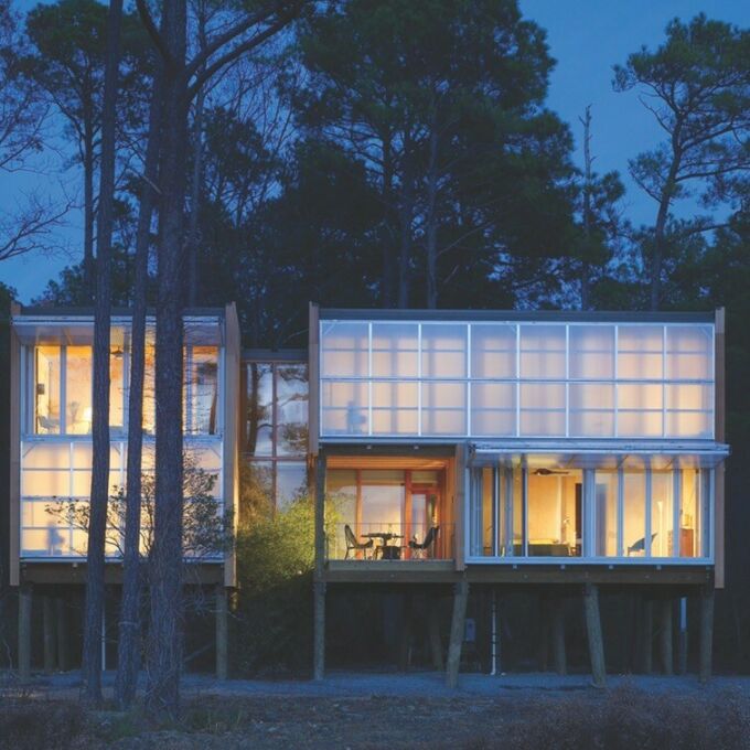 Modern residential structure elevated on stilts and featuring a with glass facade. Design by Marilia Rodrigues.