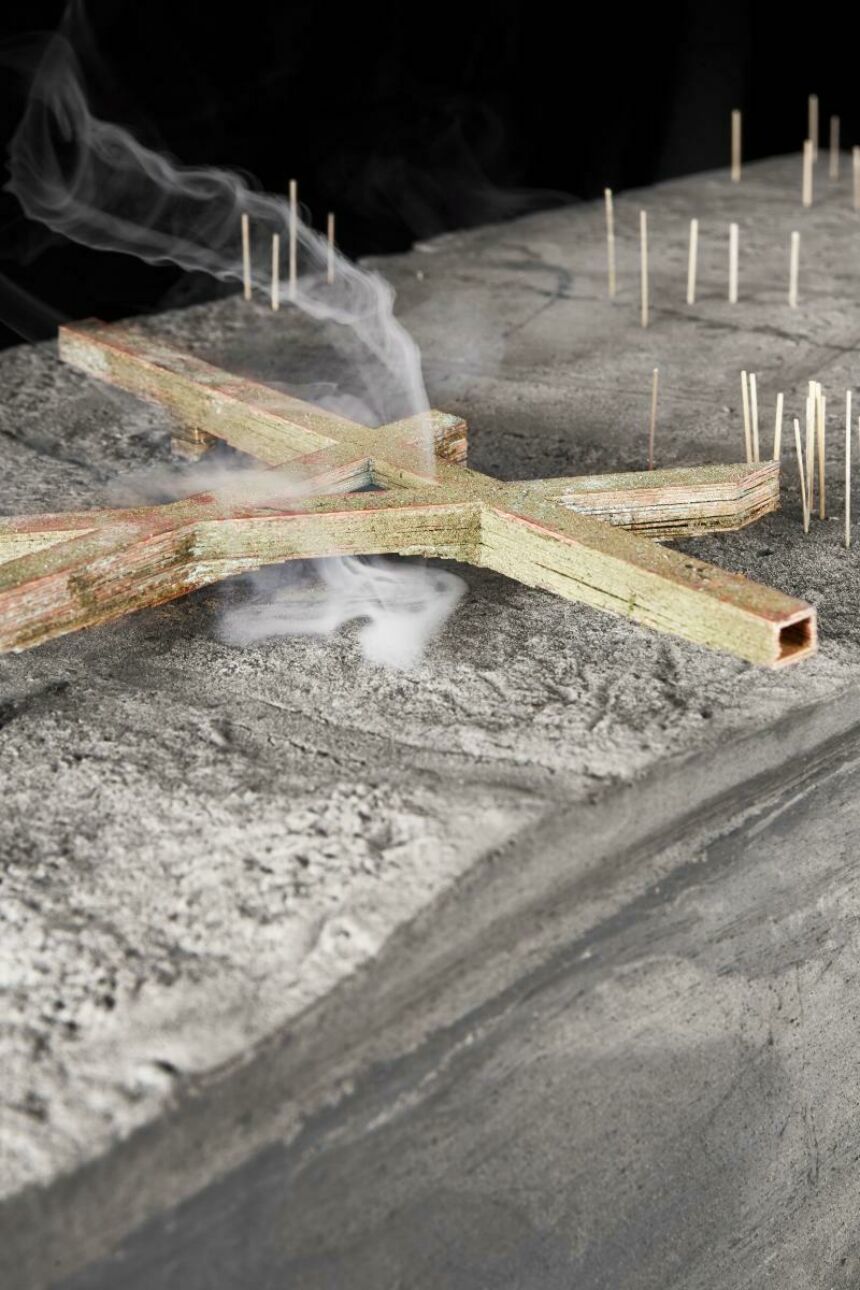 Close-up of mixed-media project of a miniature barren desert landscape with dried foliage; white smoke emanates from underneath the wood structure.