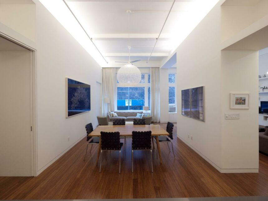 Interior photo of a modern, minimalist-style dining room, with a living room in the background.